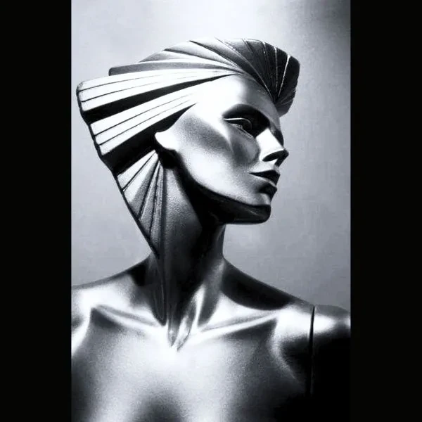 A polished silver humanoid in profile, with angular, swept-back hair.